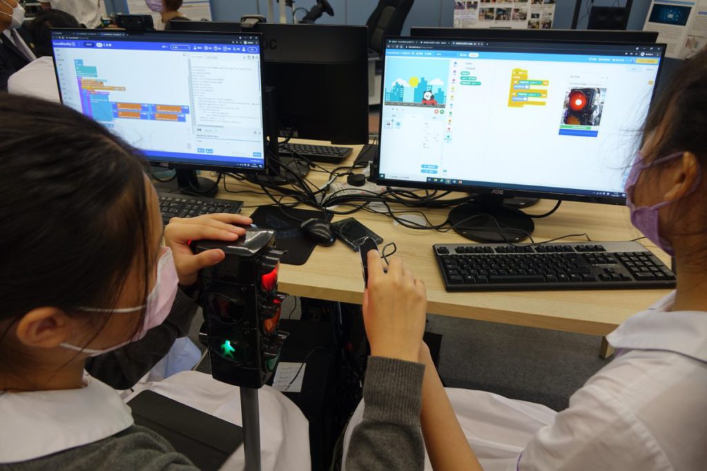 學生馮美瑤及楊菀婷正展示「紅綠燈辨識程式」，屏幕 顯示了編程內容，只需簡單的8 個步驟，而且她只花了15 分鐘已完成整個作品設計。